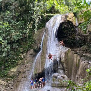 A group of people are jumping off the side of a waterfall.