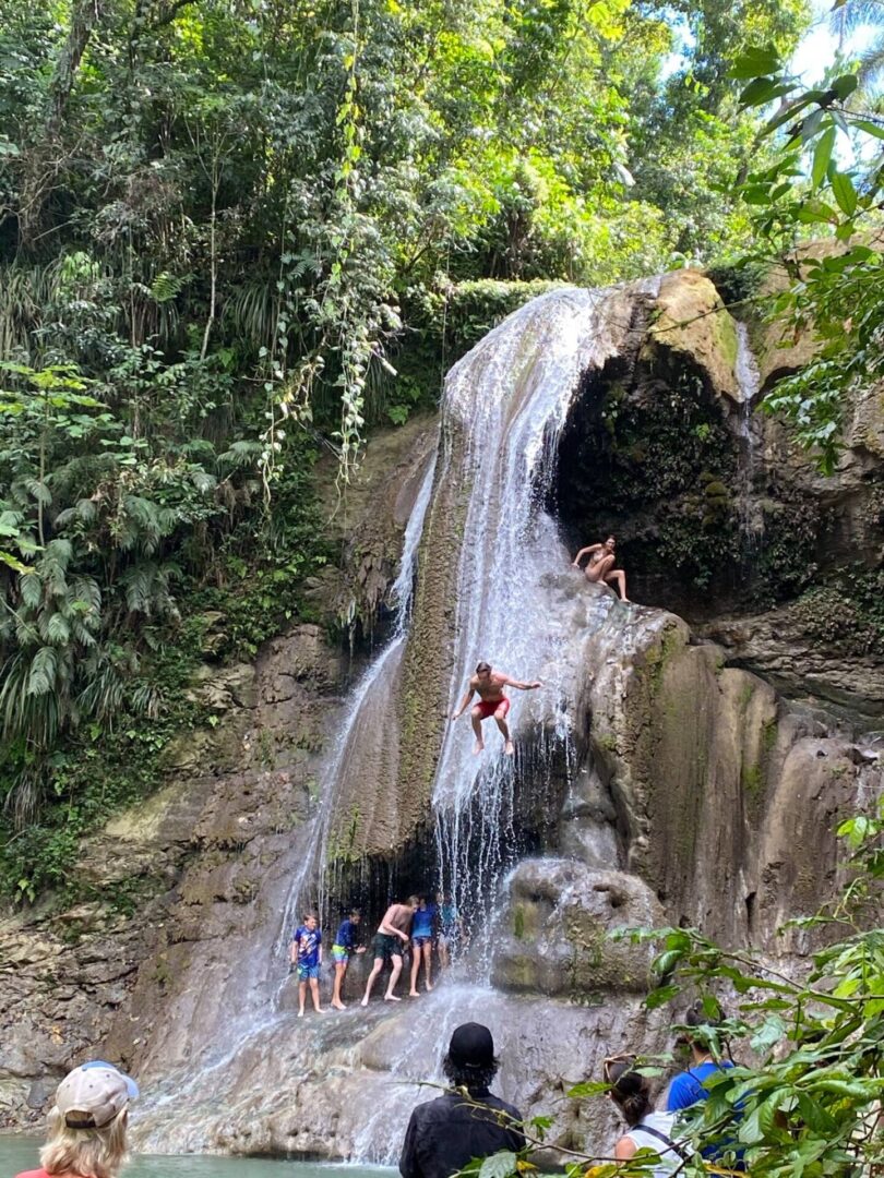 A group of people are jumping off the side of a waterfall.