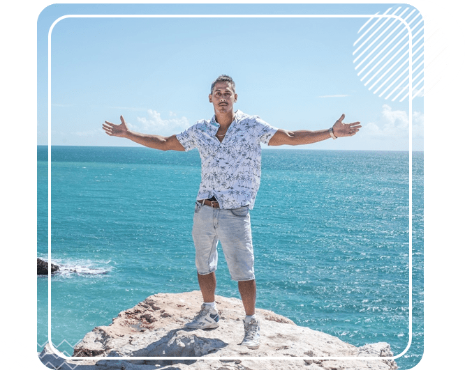 A man standing on top of a rock near the ocean.