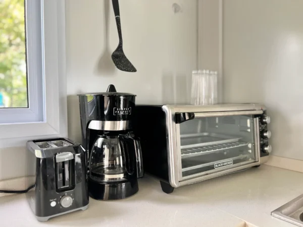 A kitchen counter with coffee pot, toaster oven and blender.